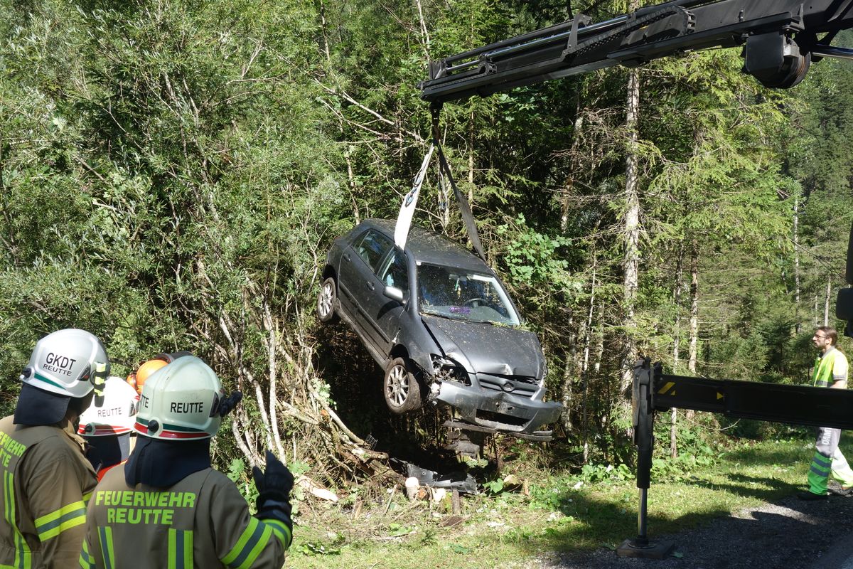 Auto wird aus der Baumgruppe mithilfe eines Kranes gehoben