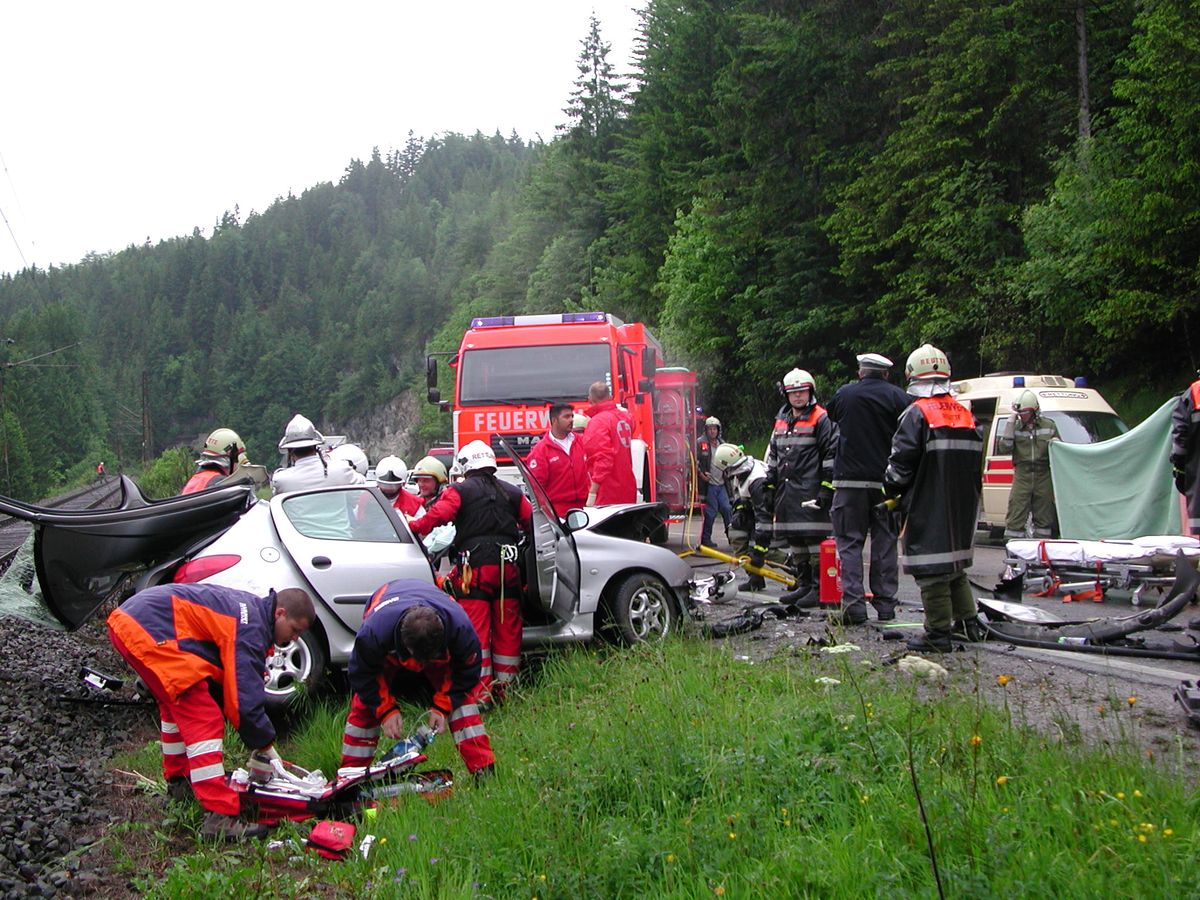 Mehrere Einsatzkräfte bei dem deformierten PKW