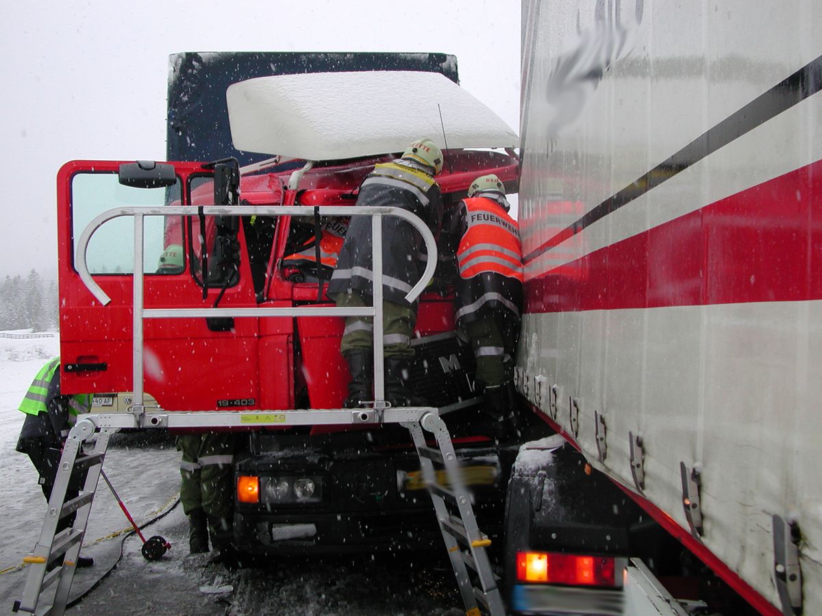 Feuerwehrleute helfen dem verletzten LKW Fahrer auf der Rettungsplattform