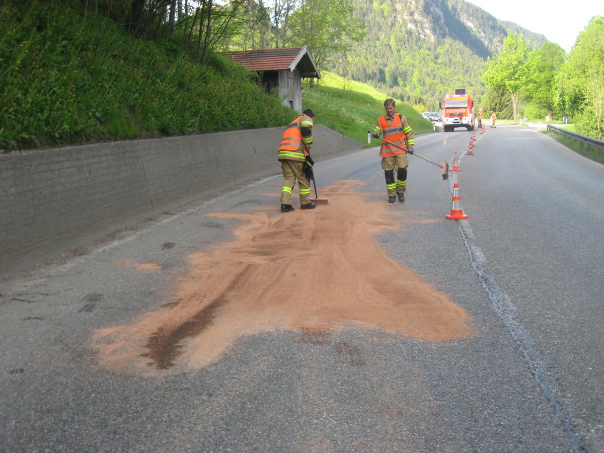 Feuerwehrmitglieder binden die Dieselspur auf der Straße